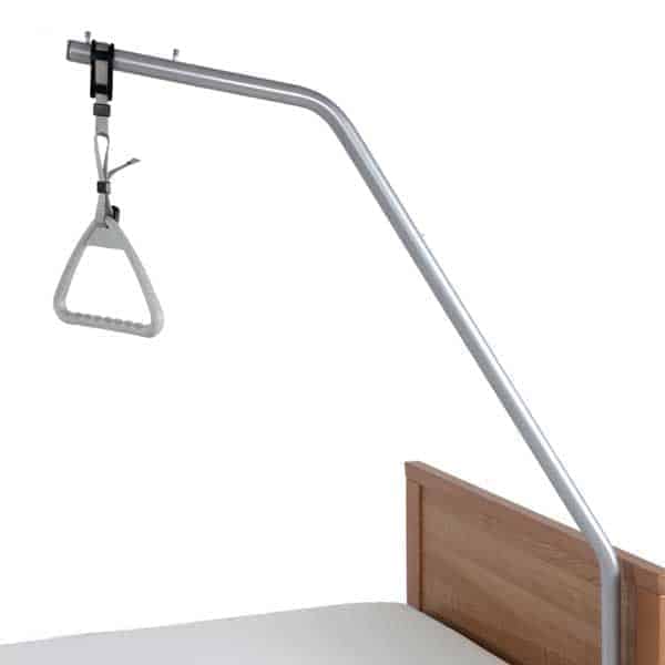 Hospital bed trapeze with a triangular handle attached to a metal frame, positioned over a bed with a wooden headboard.