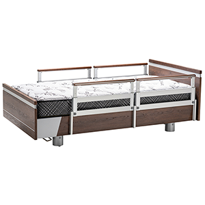 Essence 36 hospital-style bed with a wooden frame, metal side rails, and a patterned mattress, elevated on sturdy cylindrical legs.